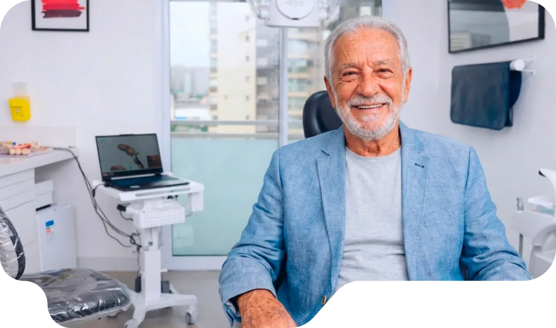 Homem idoso sorrindo na cadeira do consultório da Vital Odonto Implantes