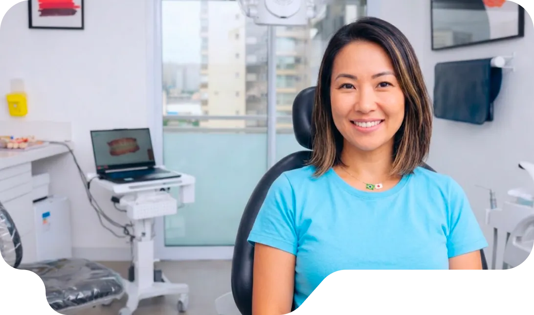 Mulher sorrindo na cadeira do consultório da Vital Odonto Implantes