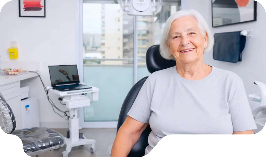 Senhora idosa sorrindo na cadeira do consultório da Vital Odonto Implantes