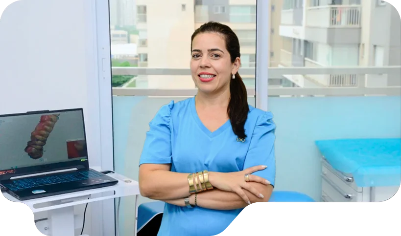 Dentista da Vital Odonto no consultório, ao lado do notebook com o escaneamento 3D de uma arcada