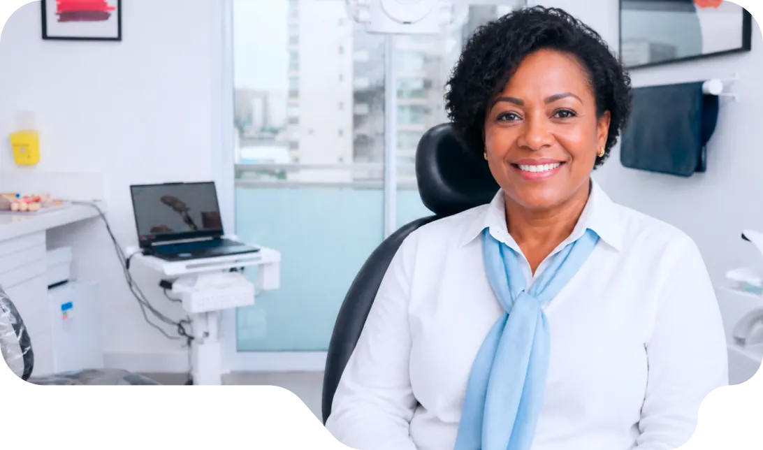 Paciente sorrindo no consultório da Vital Odonto Implantes, ao lado da cadeira